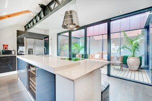A modern kitchen with a large island, built-in appliances, and a view of the outdoor deck.