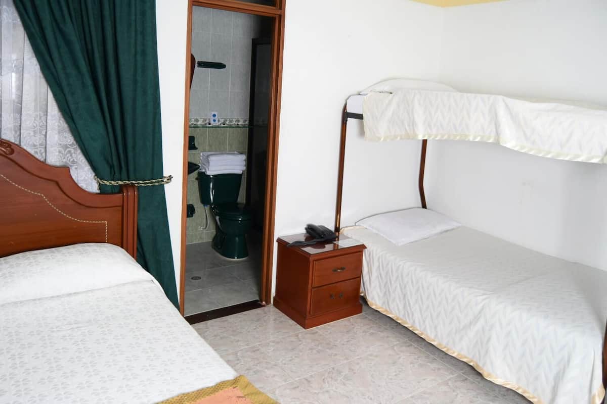 A bedroom with two single beds, a wooden nightstand with a phone, and a bathroom visible through an open door.