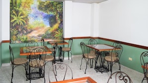 A dining area with a mural of a forest path, green walls, and metal chairs with cushioned seats. - Hotel Bolivar Plaza Manizales (Manizales)