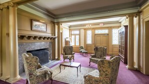 A formal room with a fireplace, multiple armchairs, a coffee table, and a large window with stained glass. - White Springs Manor a Belhurst Property (Geneva)