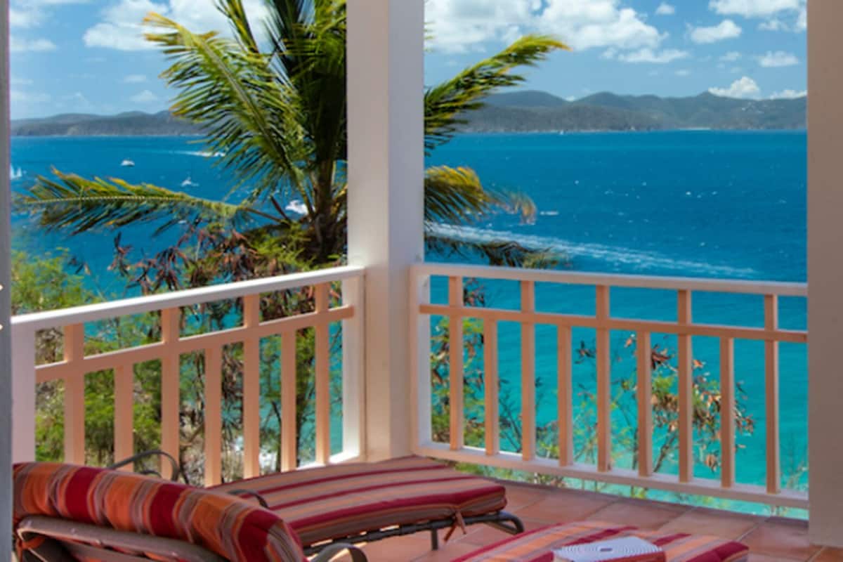 A balcony with a view of the ocean and a sailboat.
