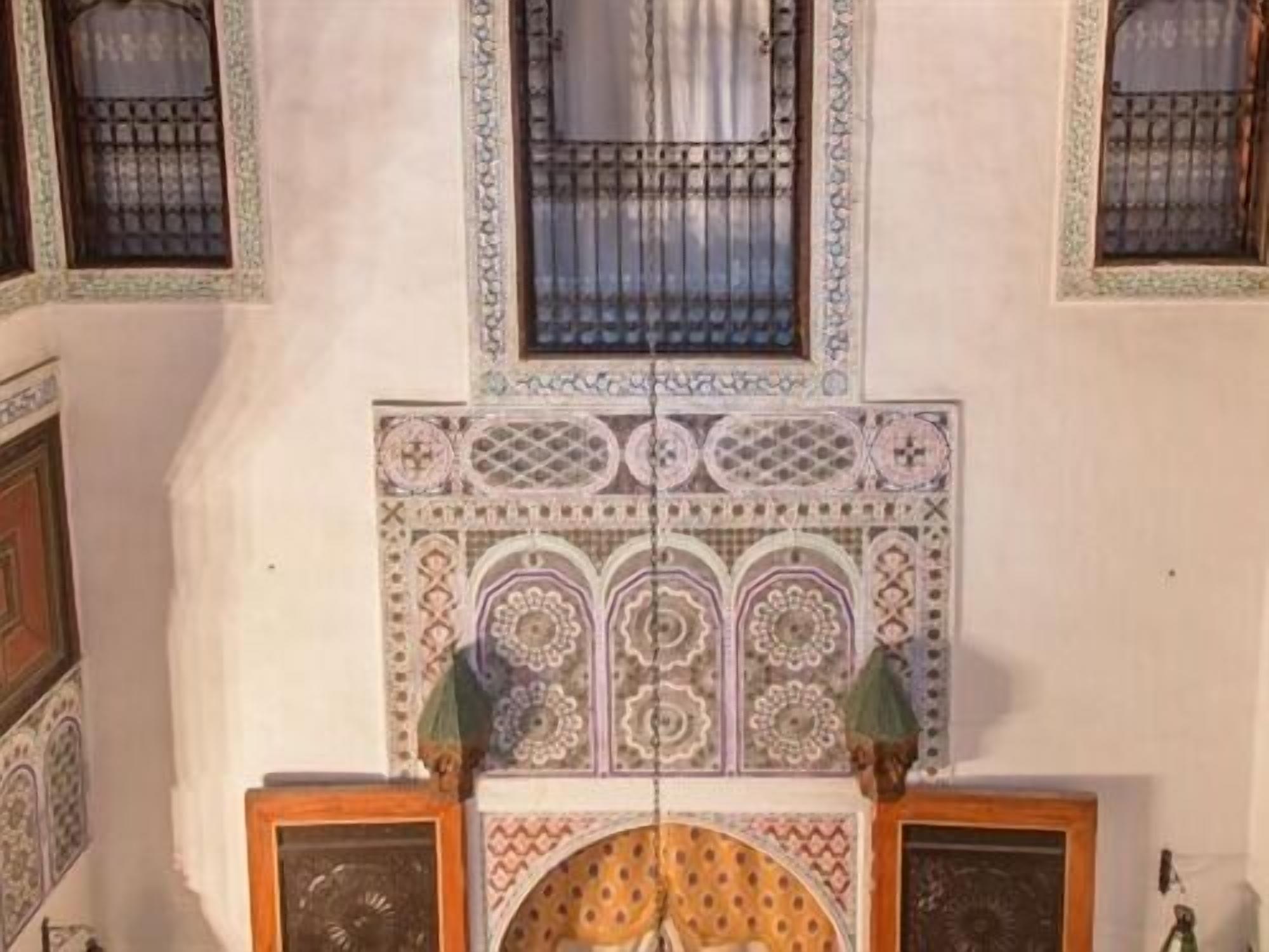 Una habitación con techo decorativo, una ventana con celosía metálica y pared estampada.