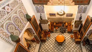 An ornate room with a central seating area, patterned floor, and intricate wall designs. - Riad Meski (Fes)