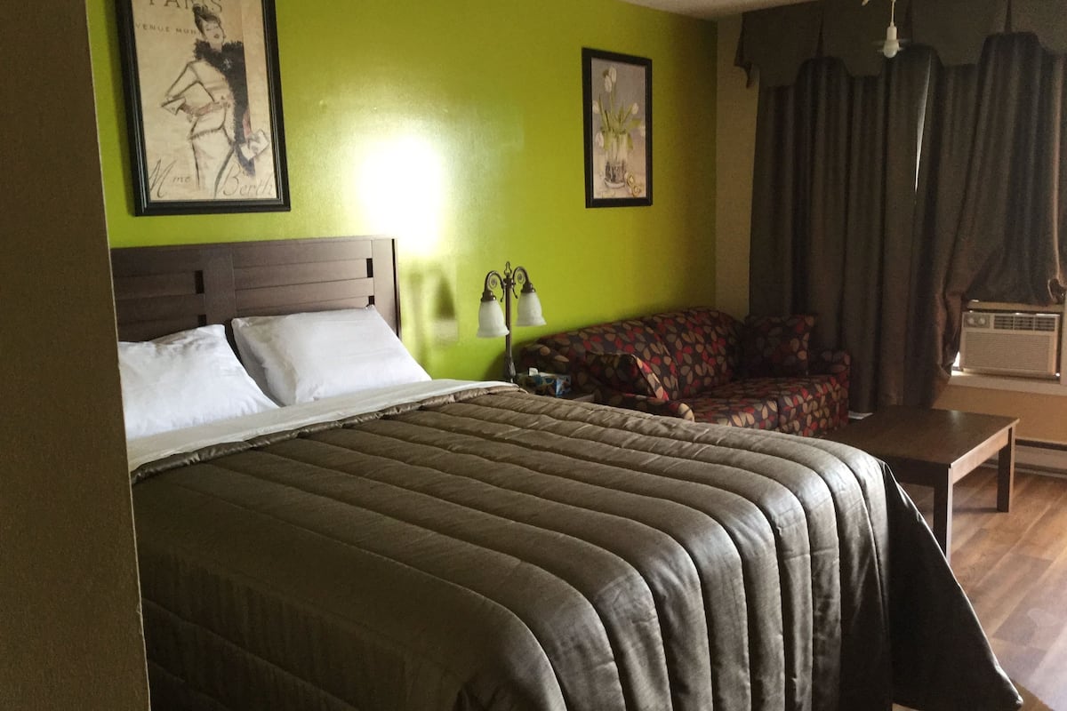 Une chambre d’hôtel avec un grand lit, un canapé et deux lampes fixées au mur.