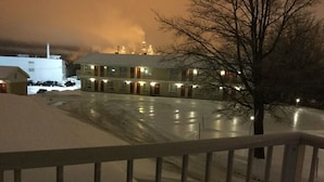 A hotel with a snow-covered parking lot and a building with multiple windows and doors. - Hotel Motel Hospitalité (Levis)