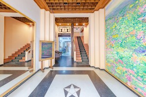 A hotel lobby with a star-patterned floor, a staircase, and a large floral mural. - Ayenda Ana Carolina (Manizales)
