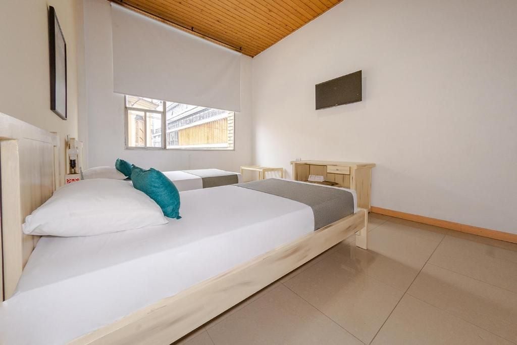 Un dormitorio con cama, mesita de noche, escritorio, ventana y vistas al exterior.