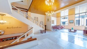 A spacious hotel lobby with a staircase, a chandelier, and a dining area. - Ayenda Ana Carolina (Manizales)