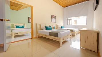 Quarto de hotel com duas camas, um armário de madeira e uma janela grande.