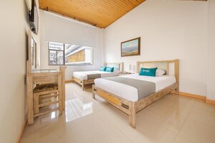 Un dormitorio con dos camas, un escritorio de madera y un ventanal grande.