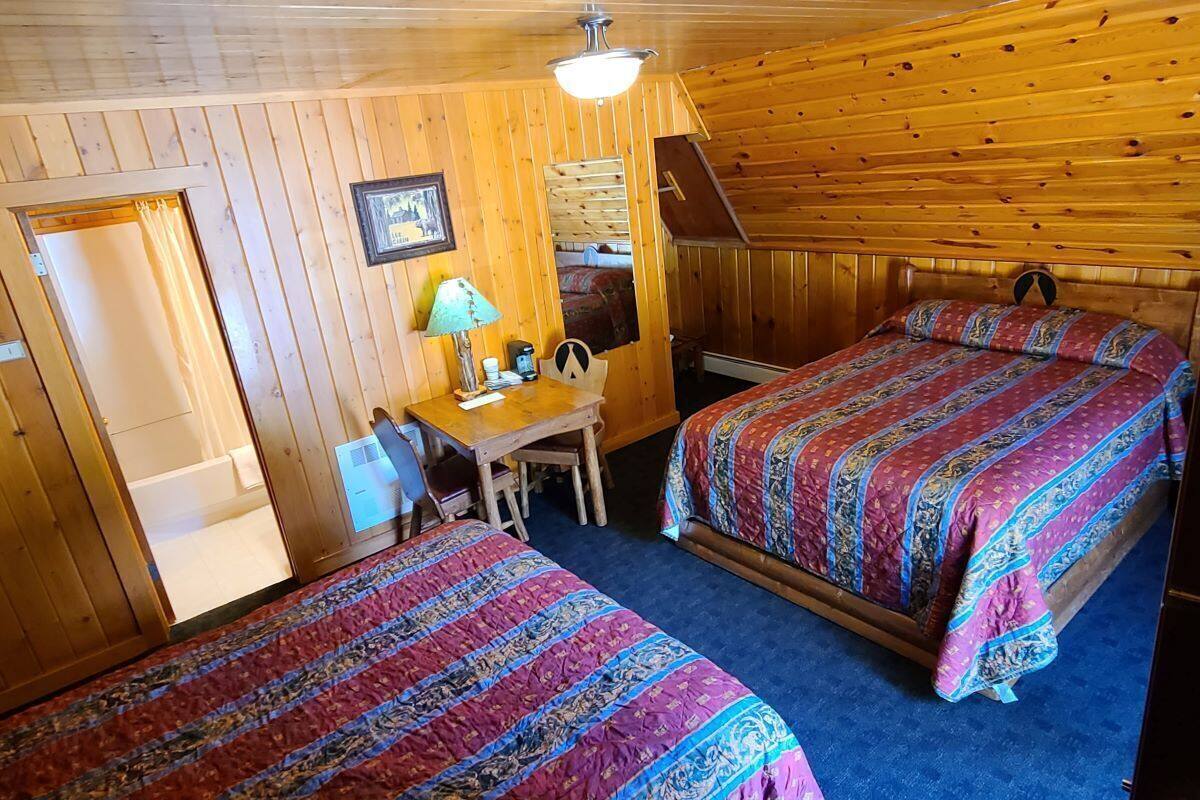 A cabin with two beds, a desk, and a chair.