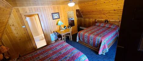 A cabin with two beds, a desk, and a chair.