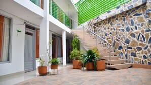 A modern interior with a stone wall, a staircase, and potted plants. - Hotel El Coliseo (Manizales)