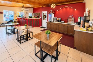 Un restaurante con pared roja, techo de madera y varias mesas con marcos negros.