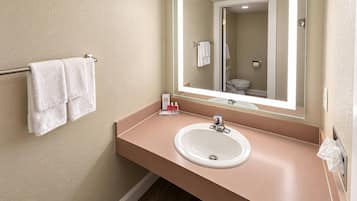 A bathroom with a beige wall, a white sink, a mirror, and a towel rack with two towels.