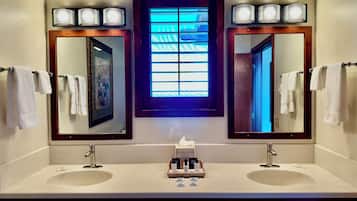Une salle de bain avec deux lavabos, un miroir et une fenêtre dotée de vitres teintées en bleu.