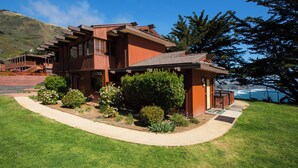A modern two-story house with a sloped roof, large windows, and a well-maintained garden with various plants and flowers.