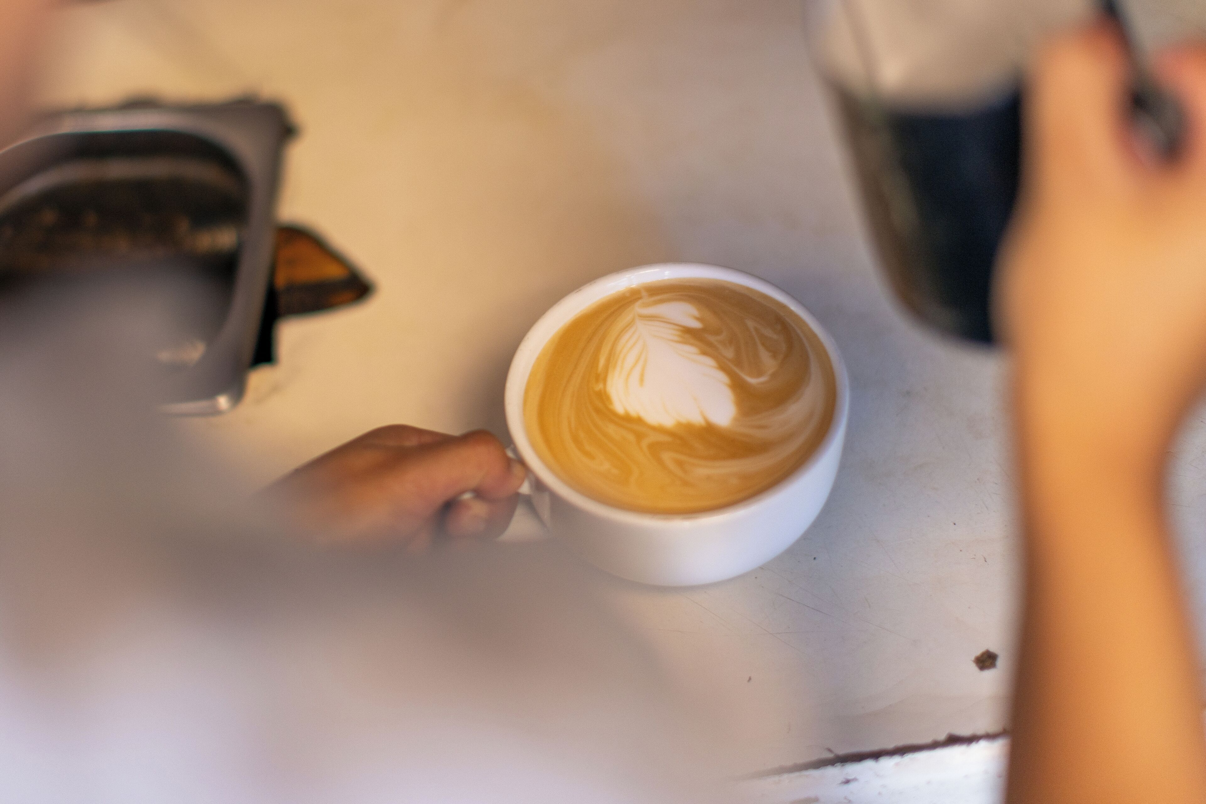 Una tassa de cafè amb dibuixos en escuma sobre una taula blanca.