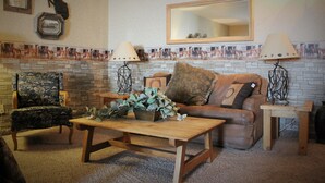 A living room with a brick fireplace, a large mirror, and a patterned rug. - Howard Johnson by Wyndham Springerville (Springerville)