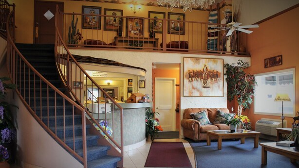 A spacious living area with a staircase, a sofa, a coffee table, and a ceiling fan. - Howard Johnson by Wyndham Springerville (Springerville)