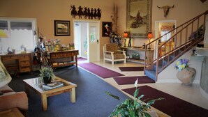 A spacious living room with a wooden coffee table, a comfortable armchair, and a staircase leading to another level. - Howard Johnson by Wyndham Springerville (Springerville)