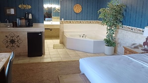 A hotel room with a bed, a small desk with a refrigerator, a sink, and a large bathtub. - Howard Johnson by Wyndham Springerville (Springerville)