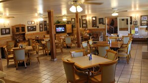 A restaurant with wooden furniture, a television, and various framed pictures on the walls. - Howard Johnson by Wyndham Springerville (Springerville)