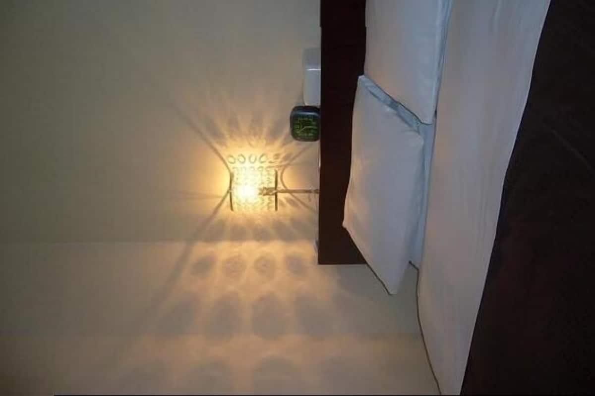 A room with a bed, a nightstand, and a wall-mounted light fixture.