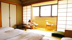 A traditional Japanese room with tatami flooring, a low wooden table with a lamp, a chair, and a sliding door. - Hiroshima Ekimae Green Hotel (Hiroshima)