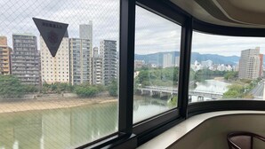 A room with a large window overlooking a cityscape, a chair, and a triangular sign with text. - Hiroshima Ekimae Green Hotel (Hiroshima)
