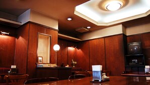 A restaurant with wooden paneling, a large table, chairs, a counter, and a television. - Hiroshima Ekimae Green Hotel (Hiroshima)
