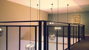 A modern interior with a glass railing, pendant lighting, and a framed picture on the wall.