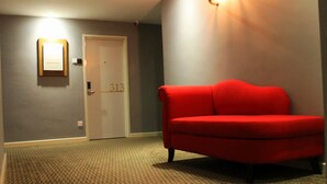 A room with a red sofa, a door with the number 313, and a framed picture on the wall.