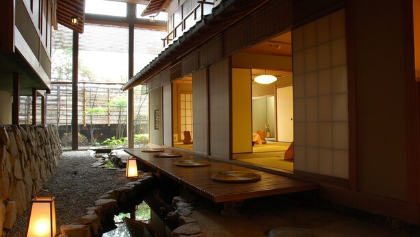 Ein traditionelles japanisches Interieur mit Tatami-Böden, einem Holztisch und Laternen.