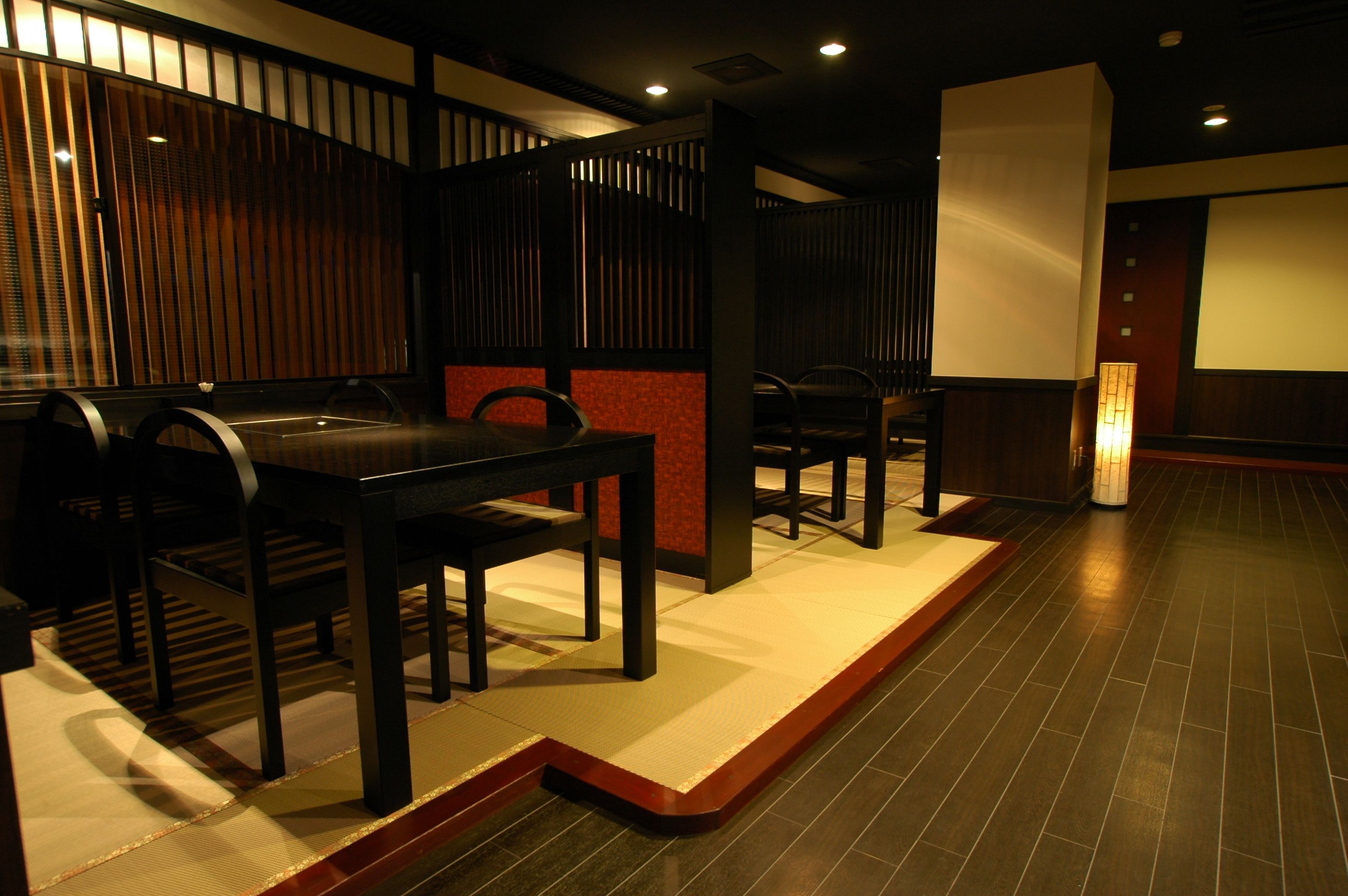A modern interior with a seating area featuring black chairs and a low table, a wooden partition, and a tiled floor.