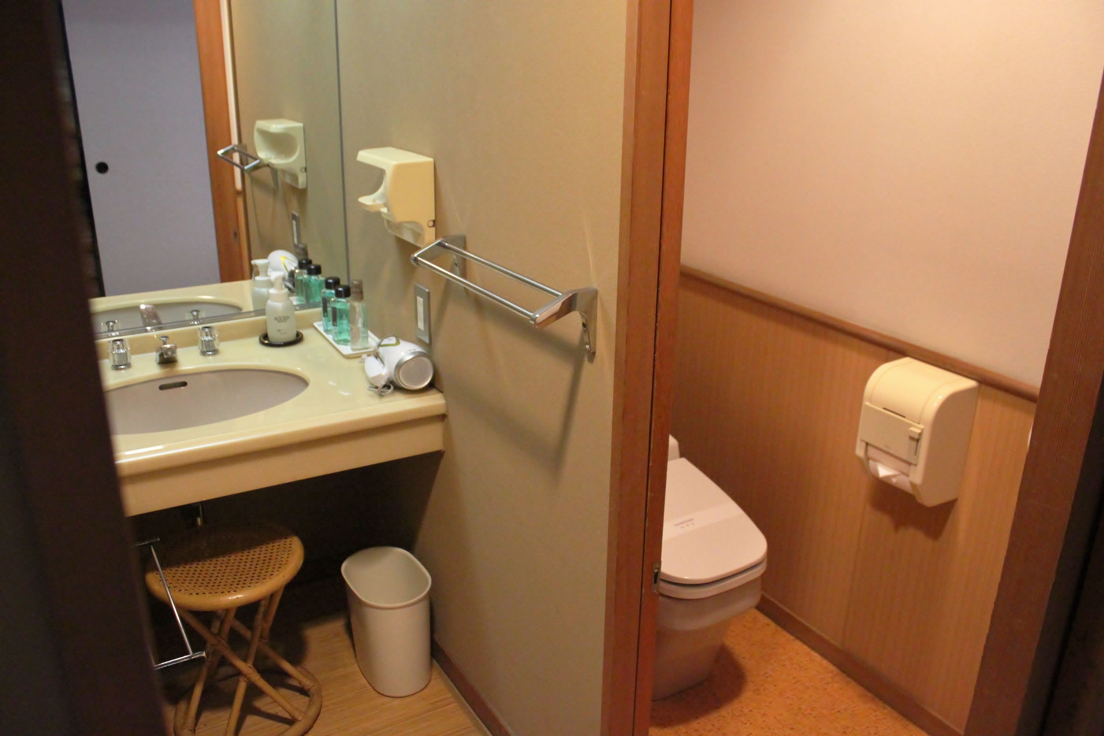 Baño pequeño con lavamanos, espejo, inodoro y secamanos.