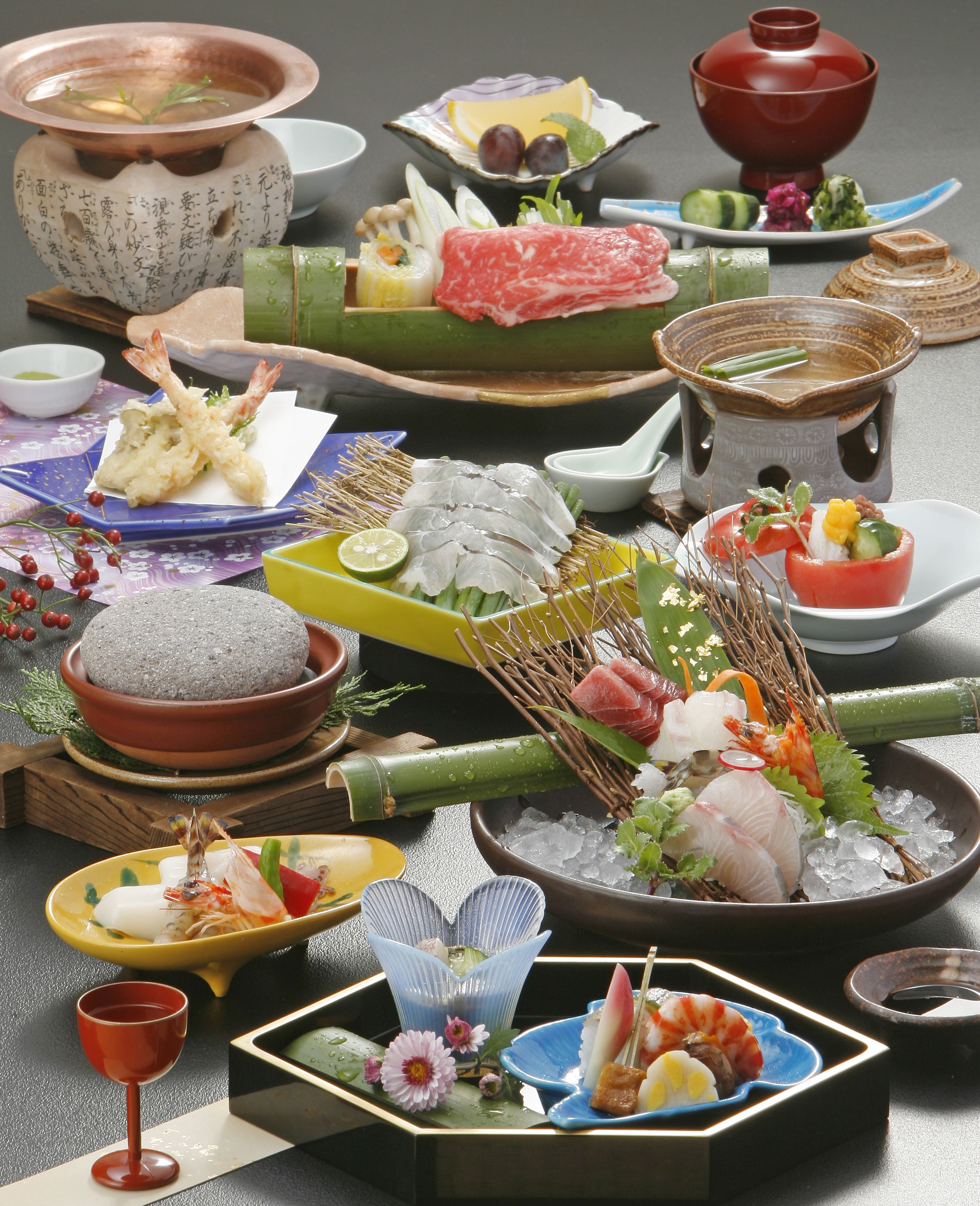 A variety of Japanese dishes, including sushi and sashimi, arranged on a table with traditional ceramic and glassware.
