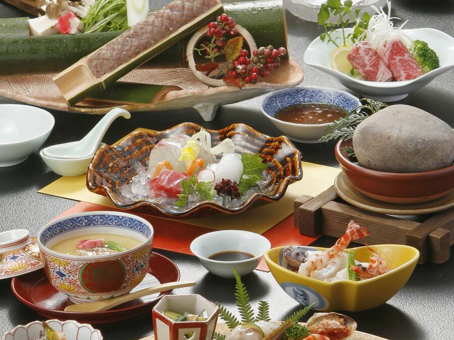 A variety of Japanese dishes arranged on a table, including sushi, sashimi, and other seafood items.