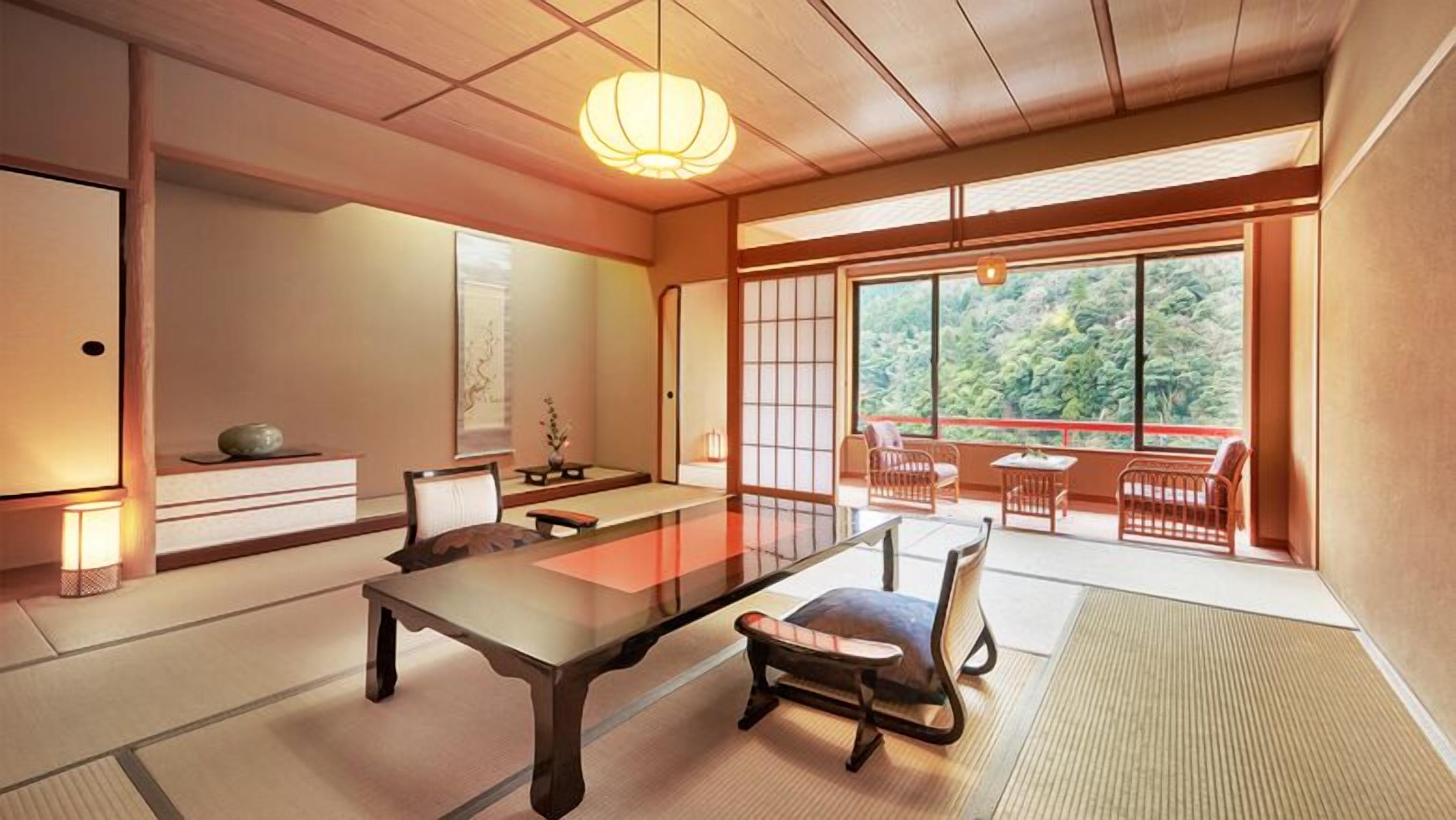 Une pièce de style japonais traditionnel, avec un sol recouvert de tatamis, une table basse et des portes coulissantes donnant sur un balcon offrant une vue sur la verdure.