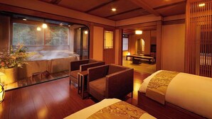 Ein traditioneller japanischer Raum mit Tatami-Böden, einem Futonbett, einer kleinen Sitzecke mit Kissen und Blick auf ein Thermalbad.