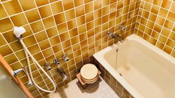 A bathroom with a bathtub, a toilet, and a shower area.