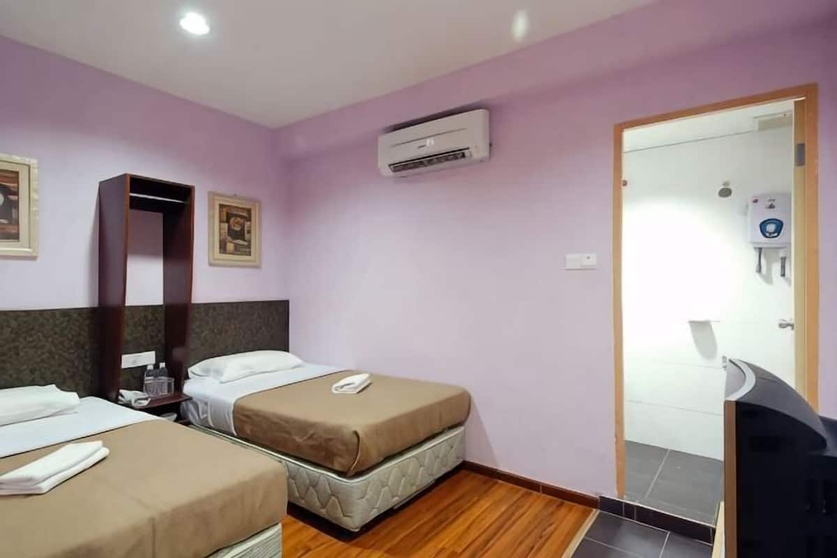 Een hotelkamer met twee bedden, een kledingkast, een airconditioningapparaat, een spiegel en een deur naar een badkamer.