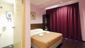 Hotelkamer met een bed, een badkamer met handdroger, een schilderij aan de muur en een raam met gordijnen.