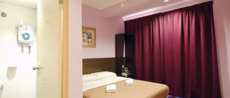 Una habitación de hotel con cama, baño con secador de manos, un cuadro en la pared y ventana con cortinas.