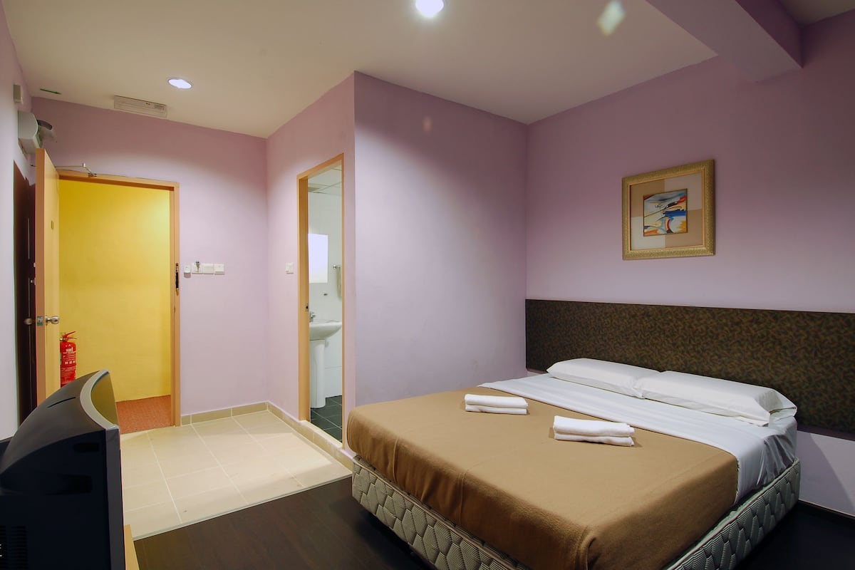 Een hotelkamer met een bed, een bureau en een badkamer, zichtbaar door een geopende deur.
