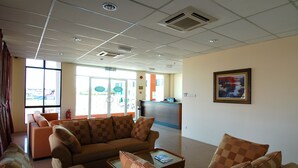 Een ruime lobby met een receptiebalie, comfortabele zitplaatsen en grote ramen met uitzicht.