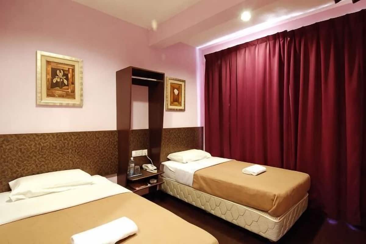 Een hotelkamer met twee bedden, een kledingkast, een spiegel en een rood gordijn.