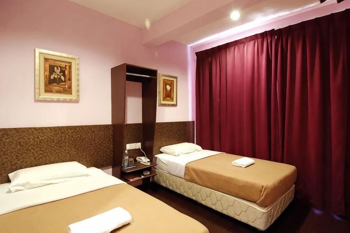 Habitación de hotel con dos camas, un armario, un espejo y una cortina roja.