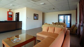 Een hotel lobby met een receptiebalie, een bank, een salontafel en een groot raam.