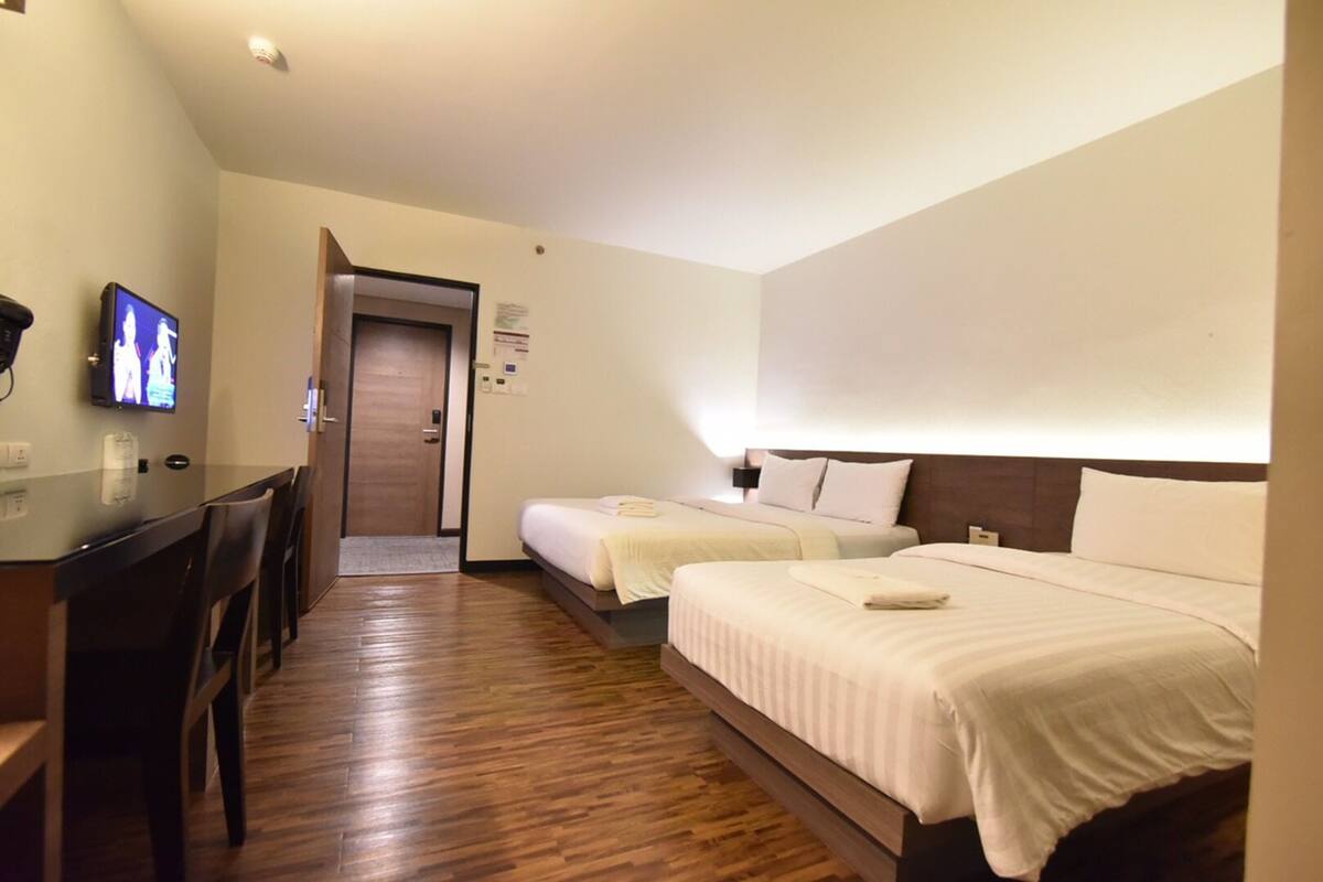 Una habitación de hotel con dos camas, un escritorio y televisión.